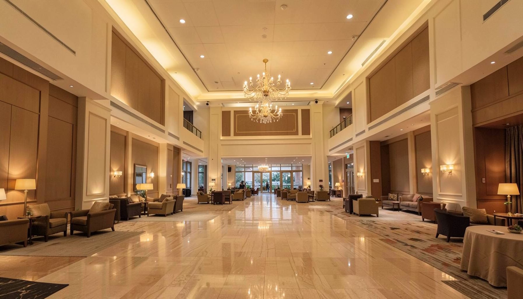 Large convention center interior with warm ambient lighting, spacious atrium, and professional atmosphere in cream and brown tones