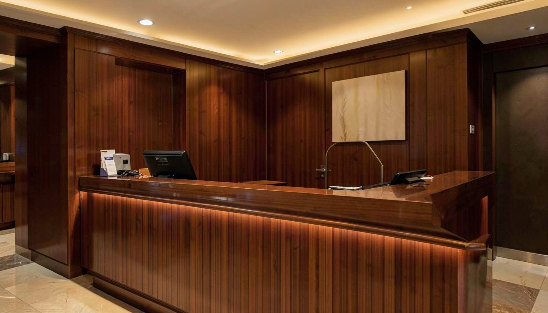 Warmly lit hotel reception desk with a polished wood counter and a subtle glow, conveying hospitality and professional service